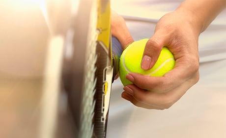 Image of a person holding tennis ball and racket